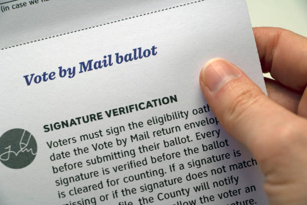 istock Hand holding paper with 'Signature Verification' Mail Voting info 1265309190