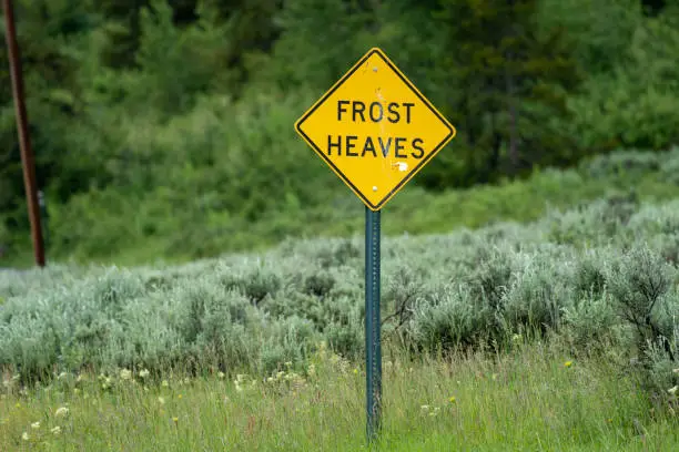 Photo of Sign warning drivers of frost heaves in the road