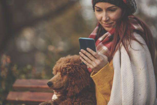 istock Relaxing on a park bench with a dog and using her smart phone 1265315624