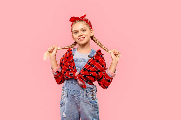 freestyle. niña en pañuelo en la cabeza de pie aislado en trenzas de sujeción rosa posando a la cámara juguetona - facial expression small empty joy fotografías e imágenes de stock