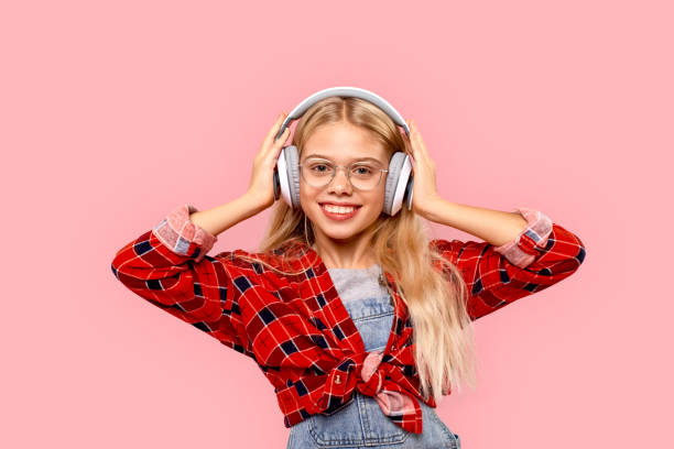 freestyle. niña en anteojos y auriculares aislados en la música de escucha rosa sonriendo alegre - facial expression small empty joy fotografías e imágenes de stock