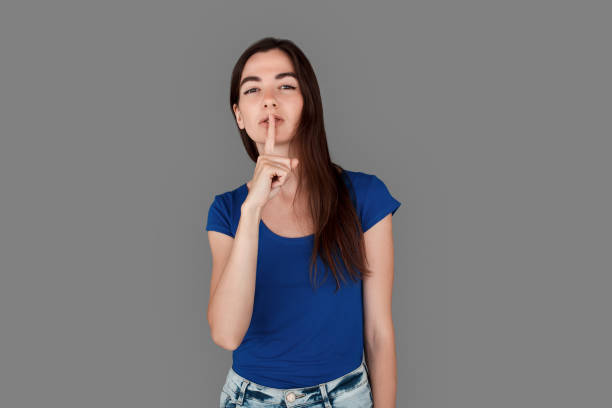 istock Young girl studio standing isolated on grey showing silence gesture serious 1265316196