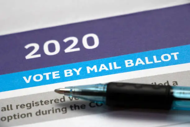 Closeup on a voter information paper with '2020 Vote by Mail Ballot' heading and pen laying on top.