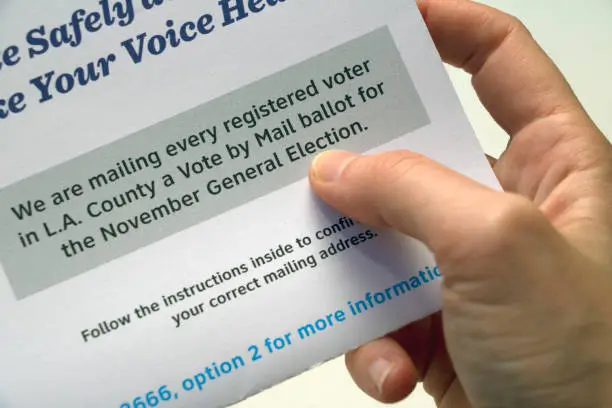 Closeup of text on a Los Angeles voting information paper held in a hand, focused on text about all registered voters receiving a Vote by Mail ballot for the November 2020 general election.