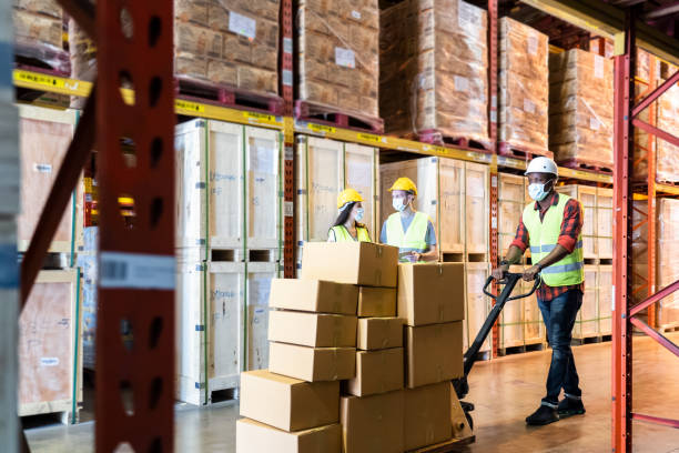 istock Group of diversity Workers wearing protective face mask working in factory warehouse. Black man pushing metal lathe cart with box parcel during covid 19 pandemic crisis. Logistic industry concept. 1265337633