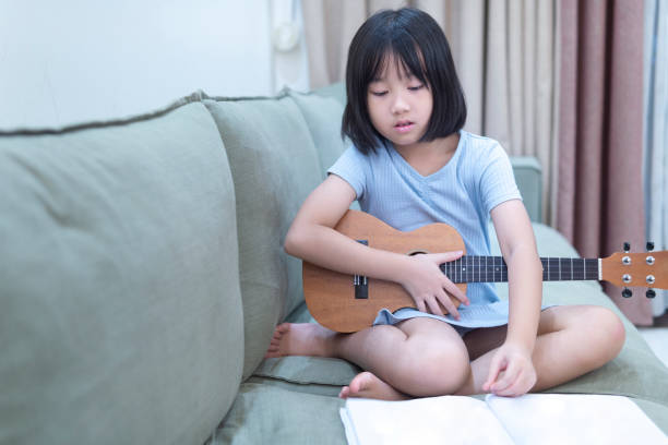 istock A little girl practicing ukulele at home 1265348577