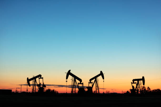 Prairie Oil Pump Jacks Canada USA Four pump jacks producing oil, Image taken near the town of Virden, Manitoba. Image taken from a tripod. grassland in morning sunrise stock pictures, royalty-free photos & images