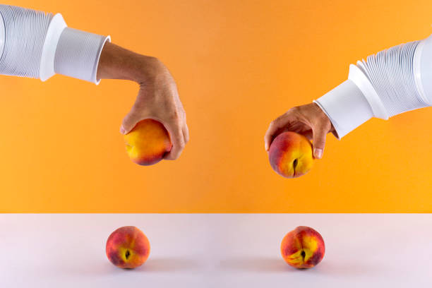 Two male hands with a peach over the table on a colored background
