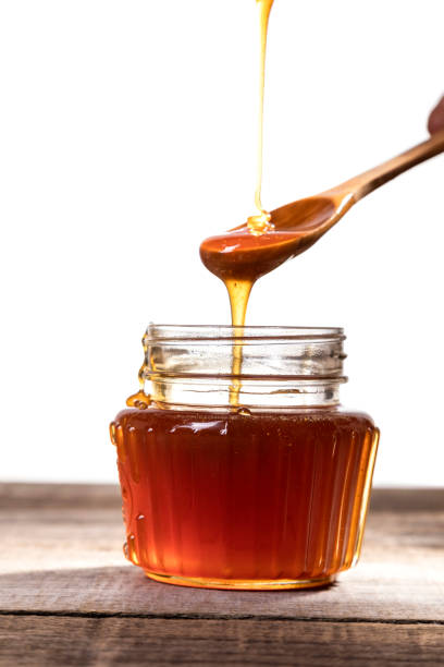 istock Honey dripping into a glass jar. 1265365840