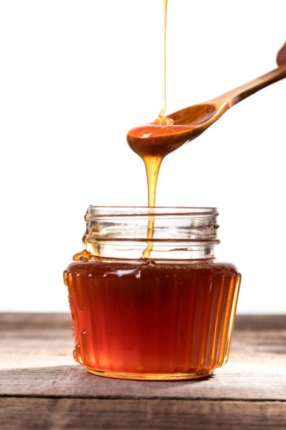 istock Honey dripping into a glass jar. 1265365844
