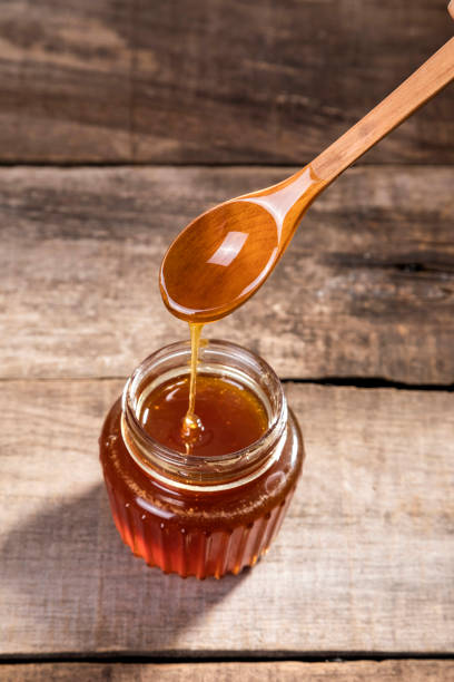 istock Honey dripping into a glass jar. 1265365870