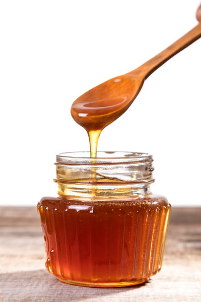 istock Honey dripping into a glass jar. 1265365882