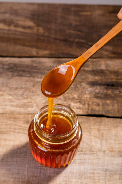 istock Honey dripping into a glass jar. 1265365889