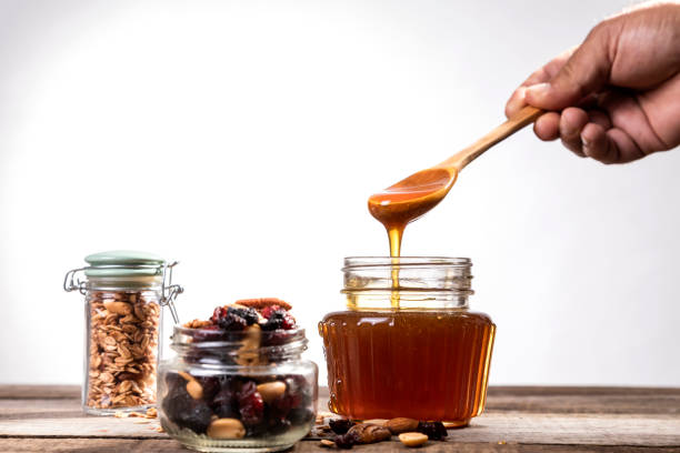 istock Honey dripping into a glass jar. 1265365890