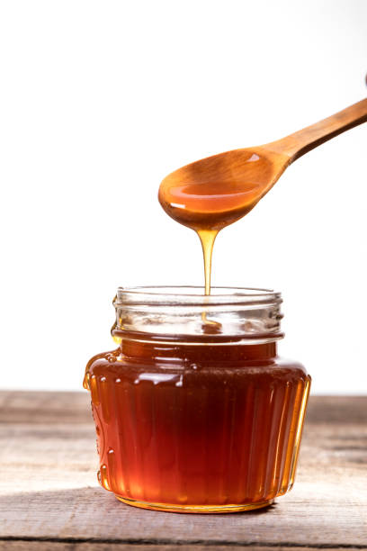 istock Honey dripping into a glass jar. 1265365931