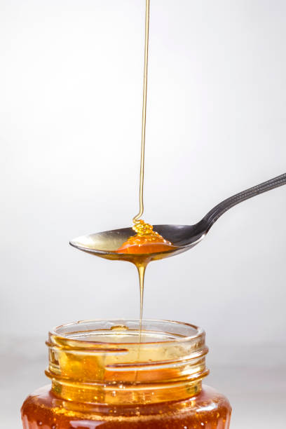 istock Honey dripping into a glass jar. 1265365945