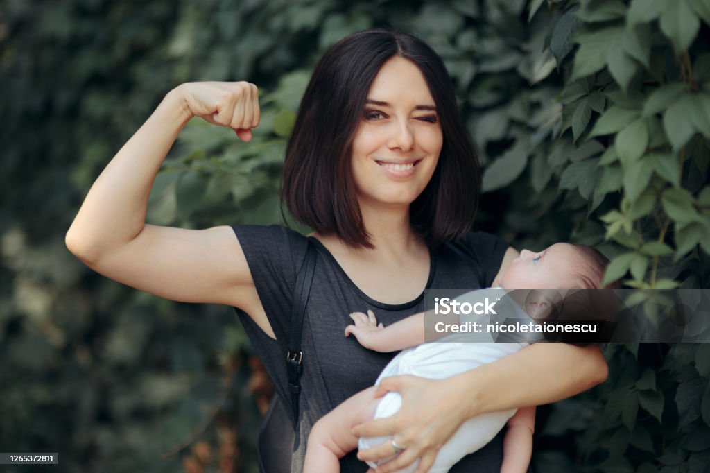 Super Mom in Strong Powerful Pose Holding Newborn Super heroine mother being a role mother to her daughter Mother Stock Photo