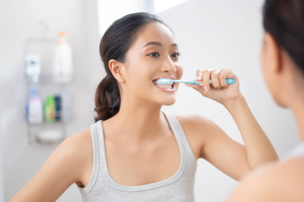 Beautiful female brushing teeth in the bathroom stock photo