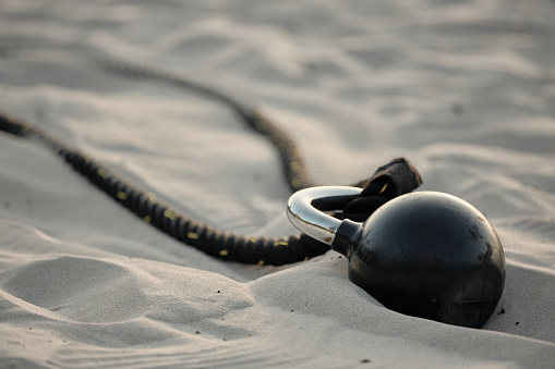 Closeup shot of a battle rope and kettle bell on the shore at the beach