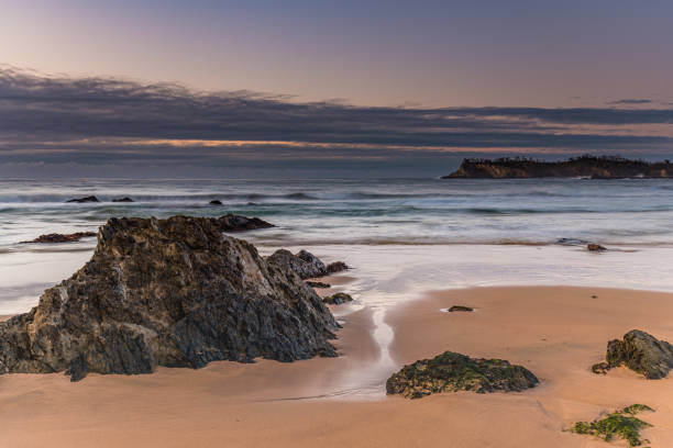 istock Sunrise at the beach with waves, rocks and clouds 1265400612