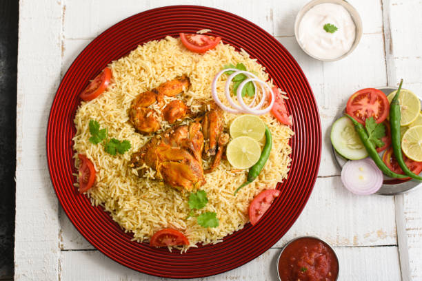 Kuzhimanthi or spicy Manthi Arabic chicken Biryani Kuzhimanthi or spicy Manthi Arabic chicken Biryani cooked meat, Basmati rice with spices in red plate on white background in Malabar Kerala, Karnataka South India. Top view of Indian non veg food. chicken madras stock pictures, royalty-free photos & images