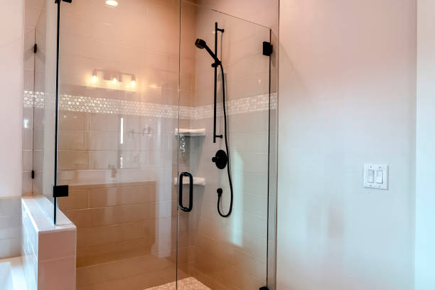 Bathroom rectangle shower stall with half glass enclosure and hinged door Bathroom rectangle shower stall with half glass enclosure and hinged door. Black shower head and soap racks are mounted on the tile wall. enclosure stock pictures, royalty-free photos & images