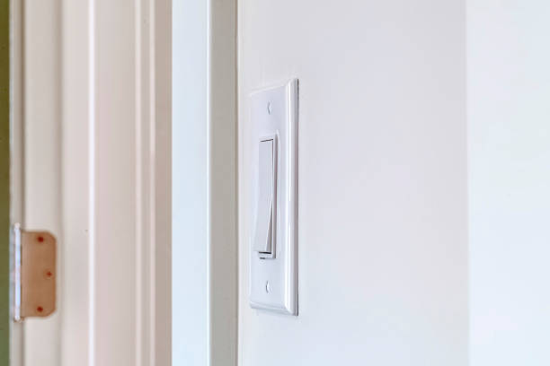 istock Side view of electrical rocker light switch mounted on white interior wall 1265418786