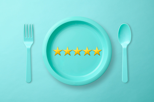 Overhead shot of blue plastic plate with five stars and folk and spoon on light blue background.