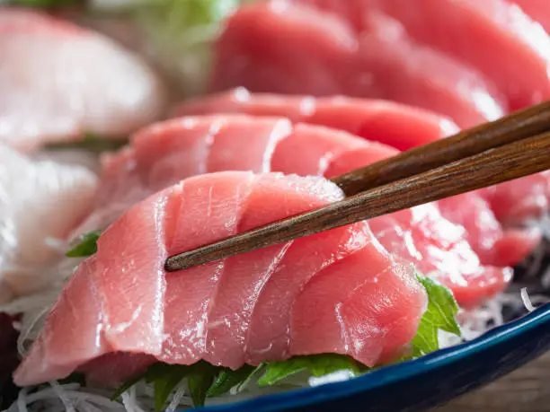 Close-up of tuna sashimi and chopsticks.
