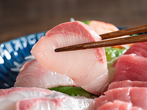 Close up of yellowtail sashimi and chopsticks.