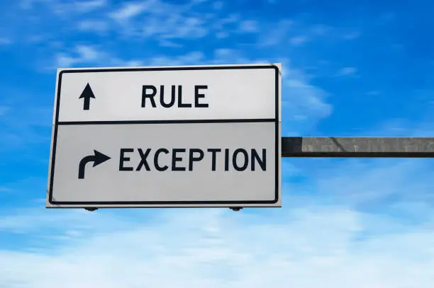 Photo of Rule versus exception. White two street signs with arrow on metal pole. Directional road. Crossroads Road Sign, Two Arrow. Blue sky background.