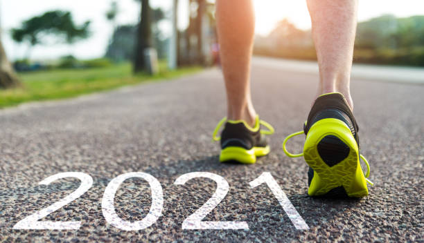 istock Man feet and number 2021 on the road 1265435621