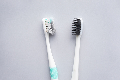 New and old toothbrushes on a gray background, close-up, flat lay. Dental and healthcare concept.