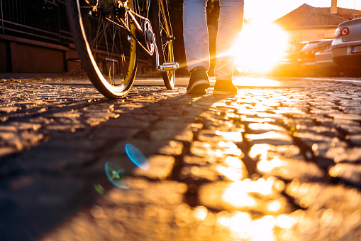 Low angle view of a unrecognisable businessman pushing a bicycle while going to work.