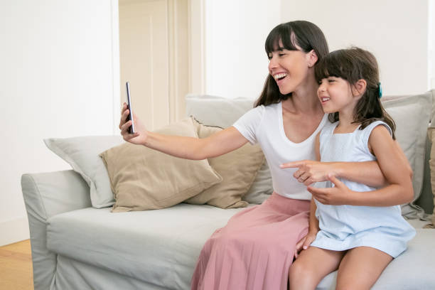 istock Cheerful mom and little daughter using phone for video call 1265446635