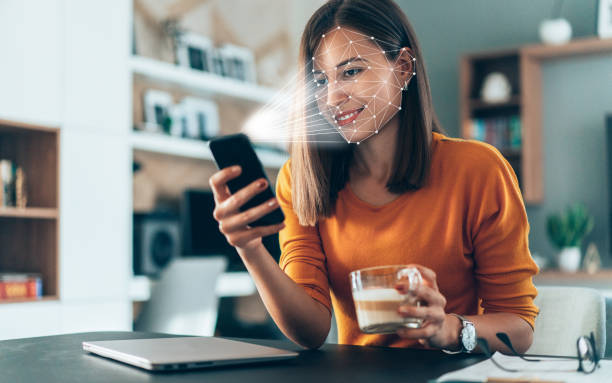 Biometric verification and face detection Facial recognition software scans the face of young woman holding smart phone at home biometrics photos stock pictures, royalty-free photos & images