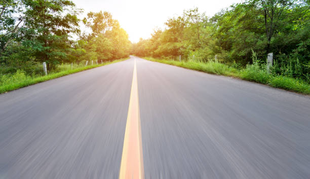 istock Motion blurred road in green forest 1265451648