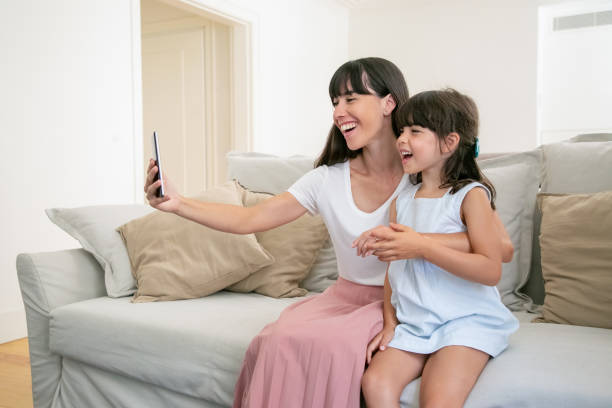 istock Happy excited mom and little daughter using phone for video call 1265451658