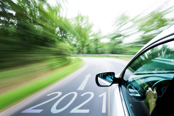istock Man hand driving a car through a forest, with number 2021 on the ground 1265457070