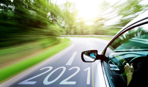 mano de hombre conduciendo un coche a través de un bosque, con el número 2021 en el suelo - color image car futuristic road trip fotografías e imágenes de stock