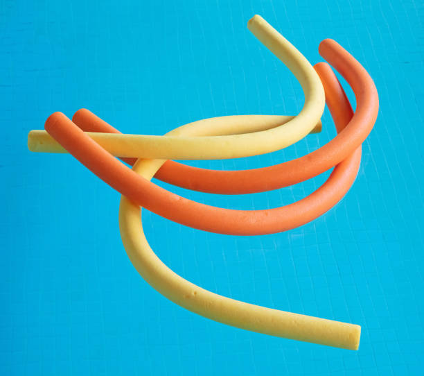 Multi coloured polyethylene hollow swim noodles floating in swimming pool