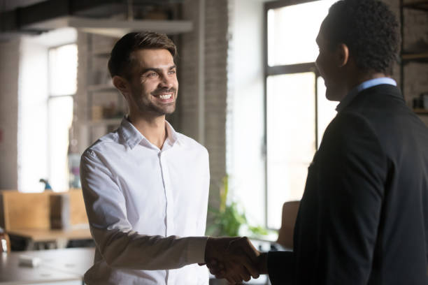 istock Smiling employee handshaking with executive, getting job or reward 1265464720