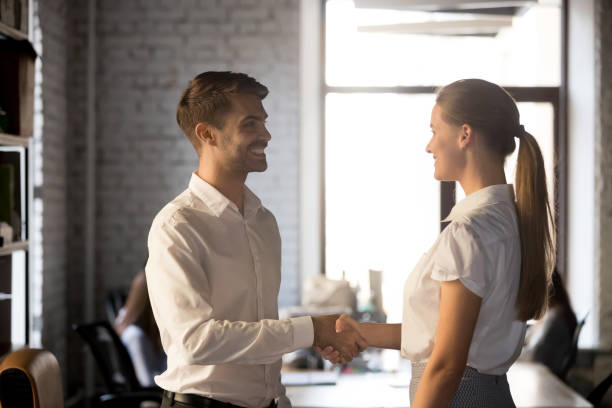 istock Smiling executive manager handshaking, greeting new hired employee 1265464740