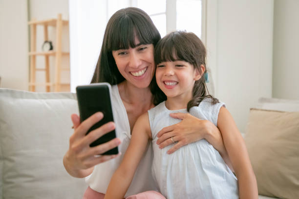 istock Cute happy girl and her mom using phone for video call 1265468155
