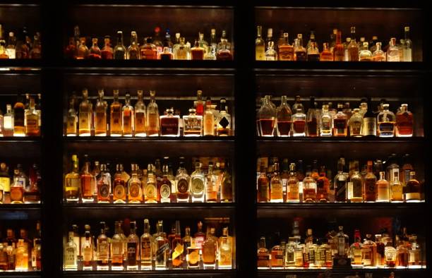 elegante pared llena de botellas de licor en un bar - bebida alcohólica fotografías e imágenes de stock