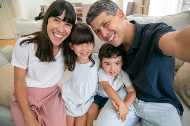 istock Joyful parents and two kids sitting on couch 1265469858