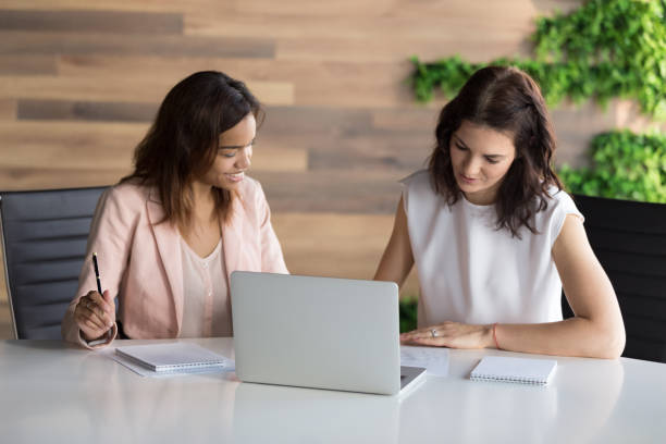 istock Diverse businesswomen, employees working on project together, using laptop 1265469981