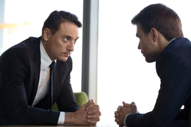 istock Confident businessmen with clasped hands sitting opposite, debate concept 1265470584