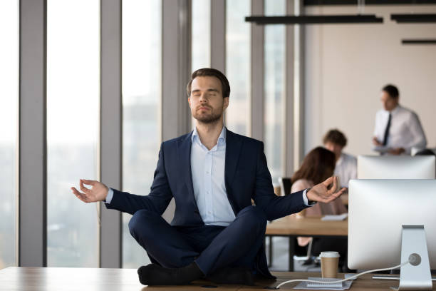 istock Calm businessman meditating on office desk, stress relief concept 1265470595