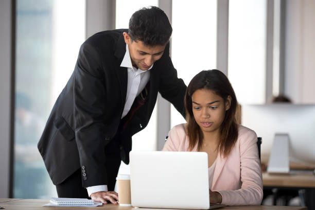 istock Friendly Arabian mentor helping African American intern with software 1265470602